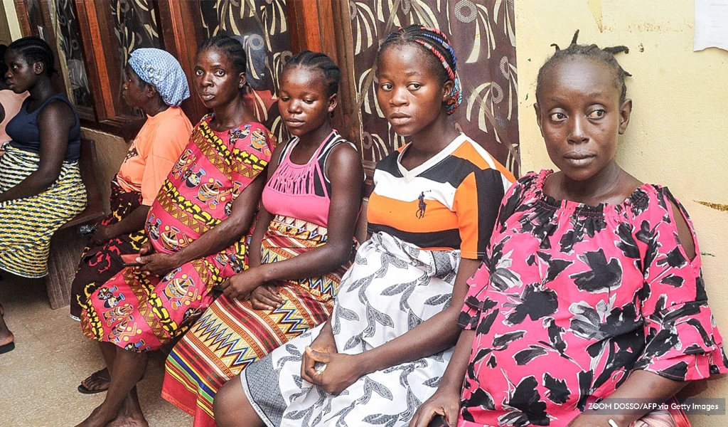 women in Liberia sitting down waiting by a wall